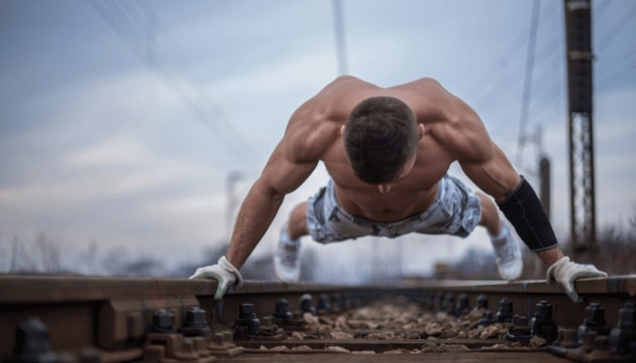 Athlete doing Calisthenics Back Exercises on railway tracks