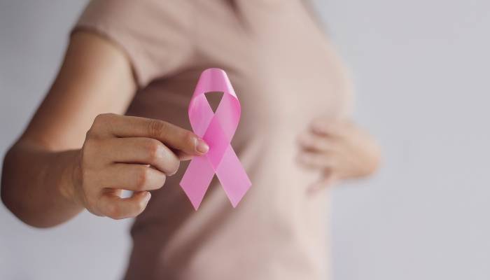 Breast Cancer Awareness: Woman holding a pink ribbon as a symbol of support and hope in the fight against breast cancer.